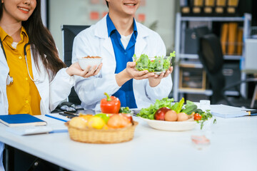 Two nutritionists,female and male, work in a hospital, analyzing vegetable and fruit salads,...