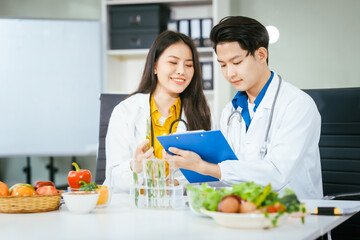 Two nutritionists,female and male, work in a hospital, analyzing vegetable and fruit salads, offering online advice, helping patients embrace clean eating habits and weight control for better health