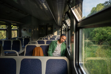 Sleepy man worn out from demanding workday, naps on an empty train ride home. Tired male backpacker on public transit, urban travel, daily exhaustion and early rise, week commute, train journey alone