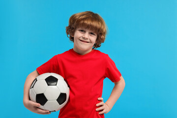 Little boy with soccer ball on light blue background