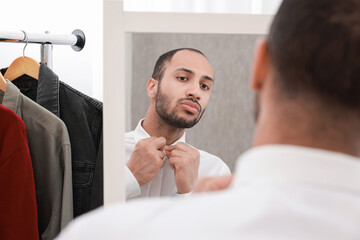 Fototapeta premium Handsome man dressing near mirror at home