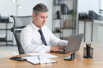 Businessman working on laptop at table in office