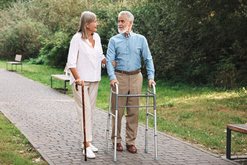Senior couple with walking frame and cane in park