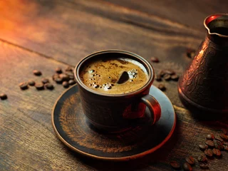 cup of Turkish coffee and cezve on a wooden table