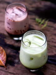 A glass of chocolate drink with a mixture of strawberry syrup flavor, and a glass of cold matcha milk. Aesthetic drink photo concept. Top view image.