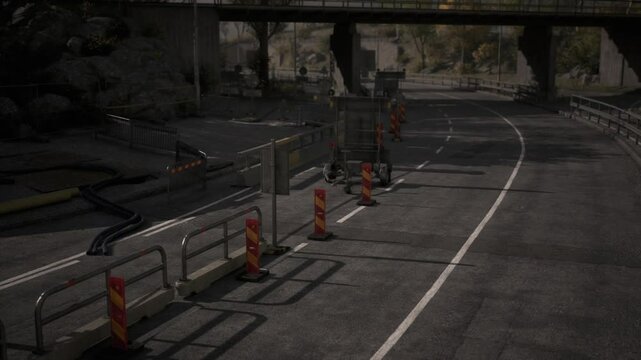 Workers are seen setting up barriers and detour signs on an unfinished road below a bridge in a busy urban area during daylight hours.