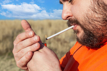 fat man with a beard lights a cigarette with a lighte