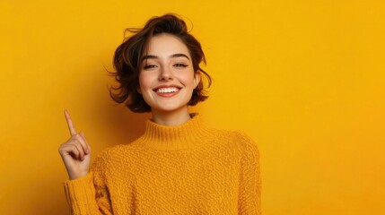 Obraz premium Portrait of a happy young woman pointing finger away at copy space isolated over yellow background