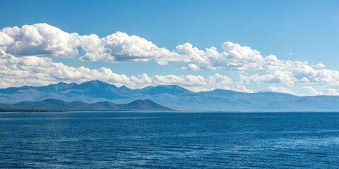 A vast blue expanse with mountains and clouds in the distance, mountains, landscape, natural beauty, outdoors, panoramic