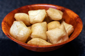 Side view of the national pastries of the peoples of Central Asia - boorsok (baursak), these are plump square dough products fried in vegetable oil, they lie in a wooden round plate.