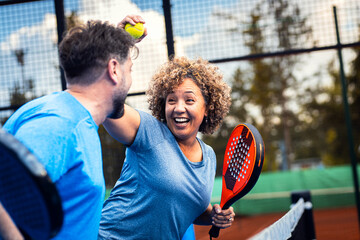 Mixed adult couple celebrate winning the point in padel on outdoor court.