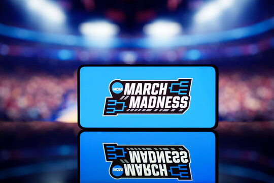 A smartphone displaying the March Madness logo with a blurred basketball court in the background.