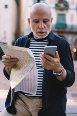 Confused old man with map using phone