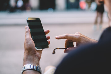 Faceless aged man using smartphone