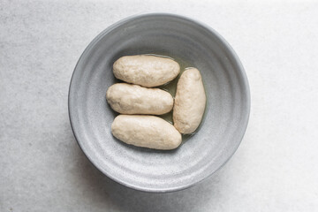 Overhead view of noodles dough in a grey bowl, top view of homemade biang biang noodles, process of making hand pulled noodles