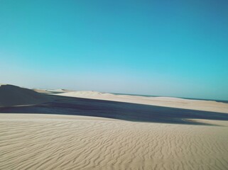 Endless sand dunes bask in solitude, their golden curves untouched by time or footfall.