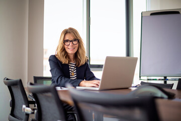 Obraz premium A middle-aged woman with blonde hair is sitting in the office working