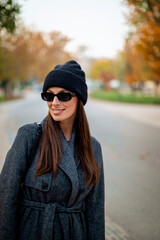 Fototapeta premium Beautiful woman walking in the city park in an autumn day