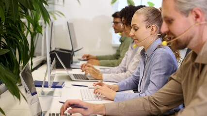 Customer service representative working in busy modern office using laptop and headset - Powered by Adobe