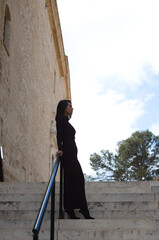 young and beautiful woman dressed in elegant violet dress leaning on the staircase railing, the woman looks at different places serious and lost because she is depressed and sad. Mental health concept