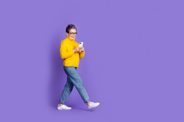 Full length photo of shiny attractive lady dressed yellow pullover chatting modern gadget empty space isolated purple color background