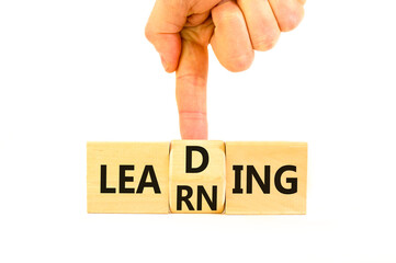 Learning or leading symbol. Concept words Learning Leading on wooden block. Beautiful white table white background. Businessman hand. Business learning or leading concept. Copy space.