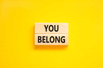 Belonging and you belong symbol. Concept words You belong on beautiful wooden blocks. Beautiful yellow background. Business belonging and you belong concept. Copy space.