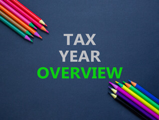 Tax year overview symbol. Concept words Tax year overview on beautiful grey paper. Beautiful grey paper background. Colored pencils. Business tax year overview concept. Copy space.
