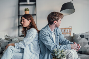 Beautiful lady is depressed, sitting on the couch talking to man, having a dispute with husband or...