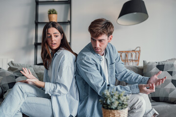 Beautiful lady is depressed, sitting on the couch talking to man, having a dispute with husband or girlfriend, looking desperate and hopeless, having unresolved problem or question.