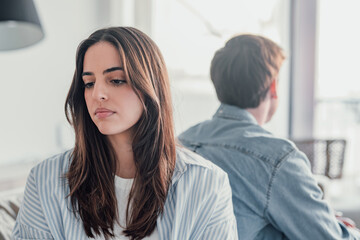 Beautiful lady is depressed, sitting on the couch talking to man, having a dispute with husband or girlfriend, looking desperate and hopeless, having unresolved problem or question.