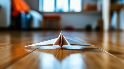 A finely crafted paper airplane sits on a wooden floor, capturing the essence of childhood creativity, playfulness, and imagination in a minimalist setting.