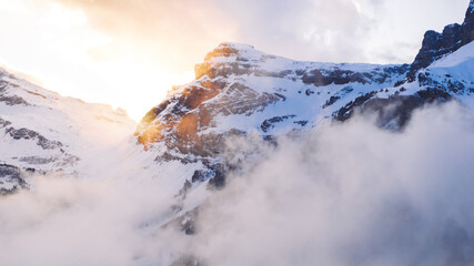 Fototapeta premium Scenery aerial view, drone flying through clouds to mountain snowy pines with frost in winter, bird’s eye view of beautiful nature landscape under breathtaking sky