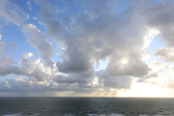 natural background with the sea below and clouds above with sunlight filtering through the clouds