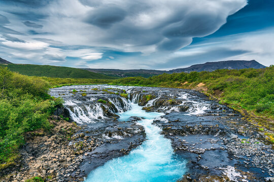 Vibrant bruarfoss waterfall flowing through rocky and wilderness in summer at Iceland