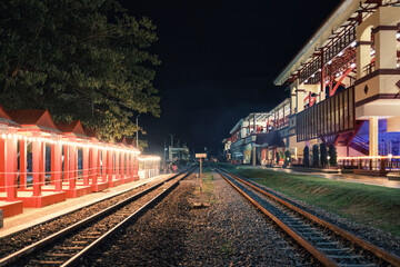 Fototapeta premium Illuminated large building of train station with railway platform in the night