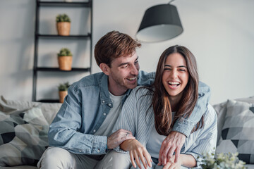Head shot positive loving bonding married couple sitting on comfortable sofa, looking at camera, holding video call with friends. Happy family bloggers recording video for personal channel at home..