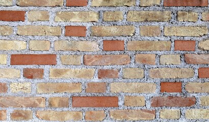Rustic brick wall with yellow and red bricks on concrete External wall covering. Full frame,...