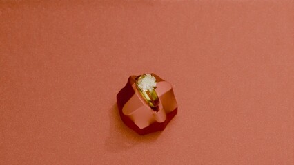 Gold solitaire ring on geometric pedestal with red background