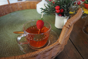 Glass cup filled with herbal drinks is adorned with a strawberry and mint, set amidst charming decorations. Selective focus. 