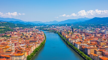 Panoramic view of a city with a river flowing through it, surrounded by mountains under a clear sky.