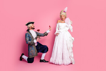 Elegant couple in historical costume on pink background showcasing romance and nobility