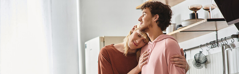 Embracing each other with smiles in a bright kitchen, showcasing their deep bond and joy.