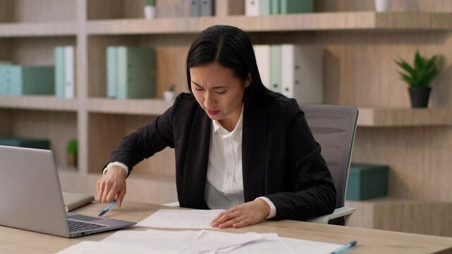Overworked stressed Asian Japanese girl office worker secretary business woman Korean ethnic female businesswoman writing notes write mistake crumple paper sheet throwing document work stress indoors