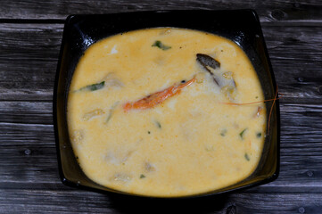 assorted seafood creamy soup of shrimps, squid, crabs, fish fillet, herbs, dill, garlic and onion, seafood mixture hot soup, healthy food concept of pieces of various sea food, selective focus