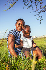 A beautiful young African woman playing with her baby boy outdoors at sunset