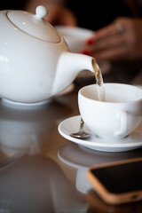 Waiter pouring tea into teacup in cafe or restaurant