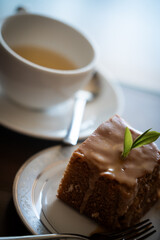 Tea leaves topping a delicious slice of honey cake with teacup in background