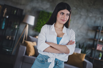 Young woman with folded arms smiling confidently in modern living room interior