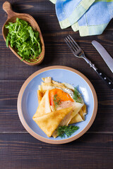 Wrapped thin pancake with filling - smoked salmon and cream cheese and pancake with scrambled egg and salmon. Crepes on blue plates. View from above, top view